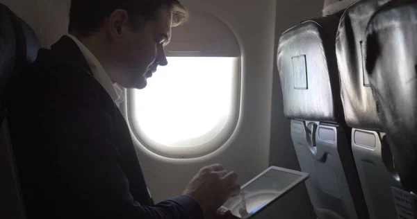 Young businessman working with pad in plane — Stock Photo, Image