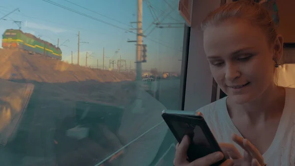 In Sankt-Petersburg, Russland, fährt ein junges Mädchen im Zug aus dem Fenster und hält ein Handy in der Hand — Stockfoto