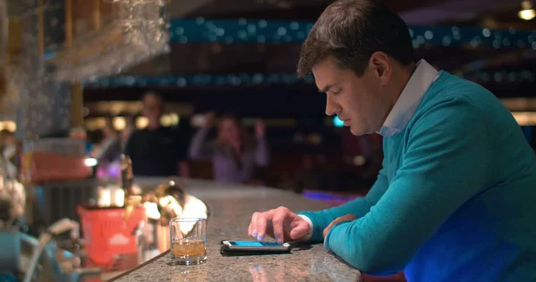 Young man typing sms on cell in the bar — Stock fotografie