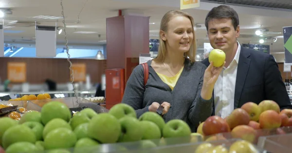 Feliz joven pareja comprando manzanas en el supermercado — Foto de Stock