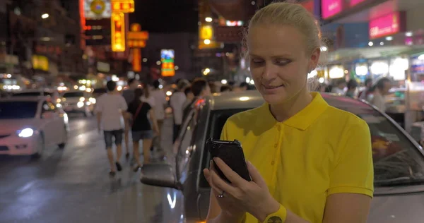 Γυναίκα γραπτών μηνυμάτων στο κινητό και κοιτάζοντας τη νύχτα Μπανγκόκ, Ταϊλάνδη — Φωτογραφία Αρχείου