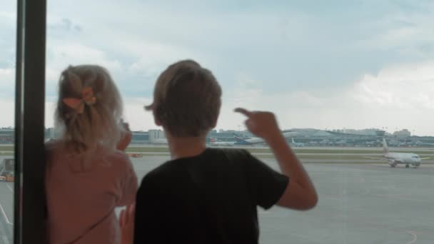 Kinder warten am Flughafen und beobachten Flugzeuge vom Terminal aus — Stockvideo