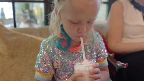 Criança bebendo delicioso milkshake no café — Vídeo de Stock