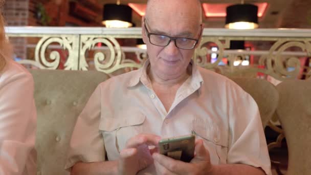 Idősebb férfi telefonnal az étteremben — Stock videók