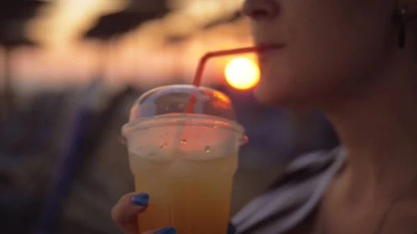 Woman having iced drink on the beach at sunset — Stock Photo, Image