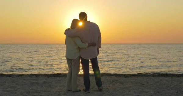 Amar pareja de ancianos disfrutando de la puesta de sol sobre el mar — Foto de Stock