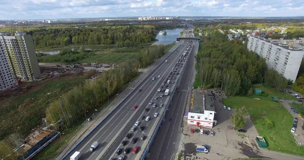 Flygfoto över en ändlös motorväg med livlig trafik mitt i det gröna stadslandskapet — Stockfoto
