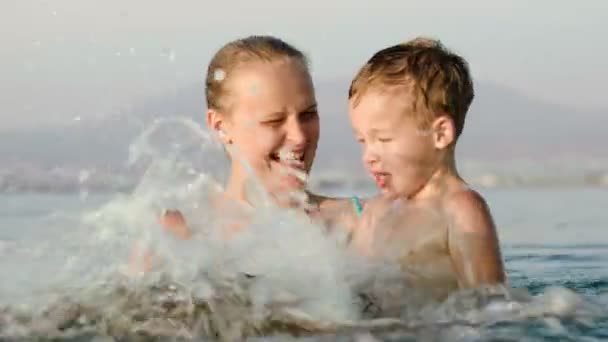 Madre e figlio spruzzando acqua — Video Stock