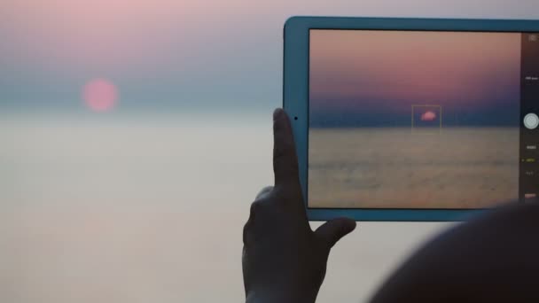 Taking pictures of sunset over sea with touch pad — Stock Video