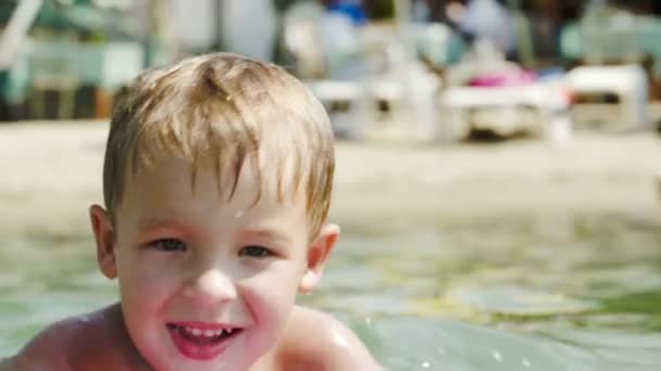 Kleiner Junge schwimmt in Ufernähe an Bord — Stockvideo