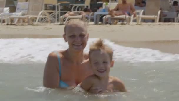 Mutter und Sohn springen mit Wellen ins Meer — Stockvideo