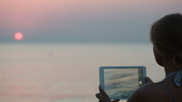 Vrouw die foto van het gebruik van zonsondergang tablet — Stockvideo