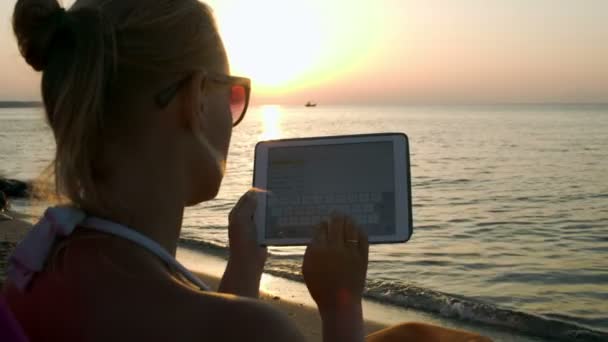 Frau tippt auf Pad sitzend am Meer — Stockvideo