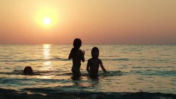 Meisjes spelen met de bal in de zee bij zonsondergang — Stockvideo