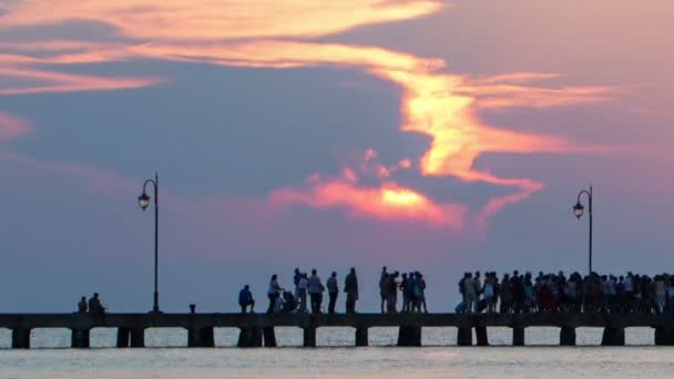 Gente caminando en el muelle al atardecer — Vídeo de stock