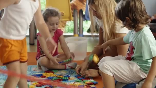 Niños y maestro de escuela en la sala de juegos — Vídeos de Stock