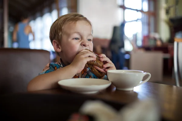 Niño comiendo sándwich en un café — Foto de Stock