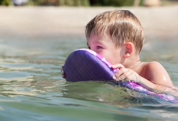 Niño nadando a bordo cerca de la playa — Foto de Stock