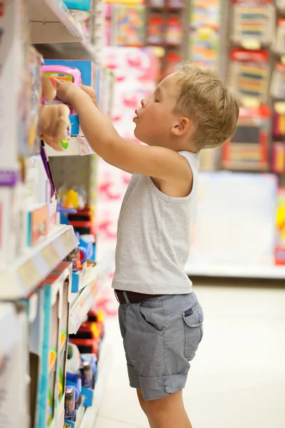 Menino escolhendo brinquedo na loja — Fotografia de Stock