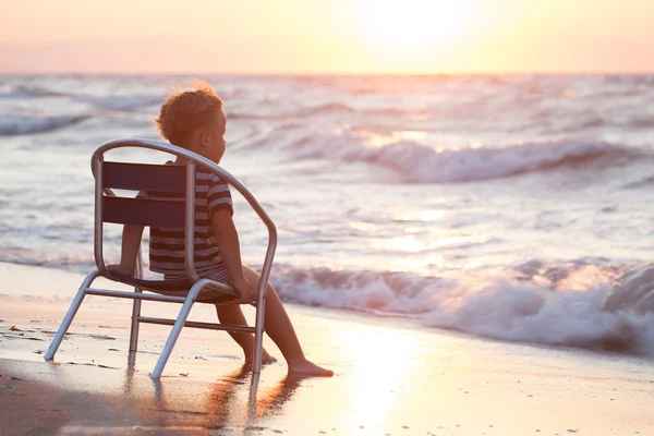 Pojken sitter på stol vid havet — Stockfoto