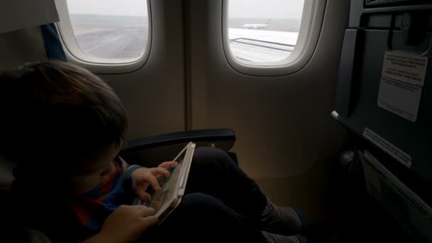 Boy using tablet PC in plane going to take off — Stock Video