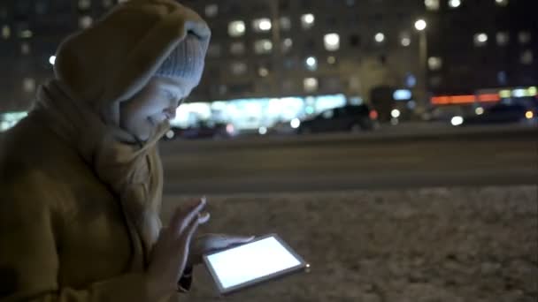 Mujer escribiendo mensaje en la almohadilla mientras camina por la noche — Vídeos de Stock