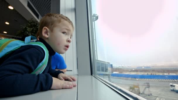 Mama i synek patrząc przez okno na lotnisku — Wideo stockowe