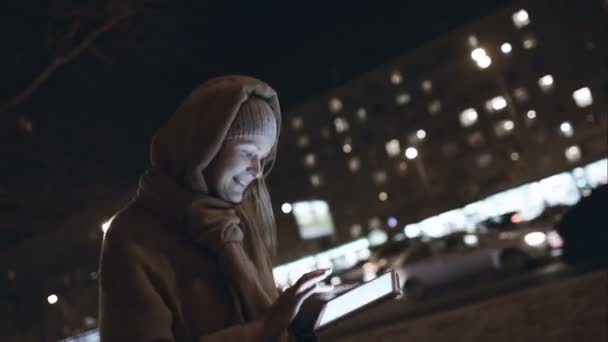 Woman with touch pad typing on her way in night city — Stock Video