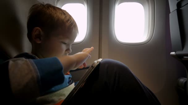 Niño jugando en la almohadilla táctil en el avión — Vídeos de Stock