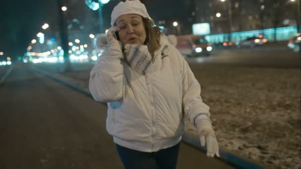 Woman having exciting phone talk during evening walk in city — Stock Video