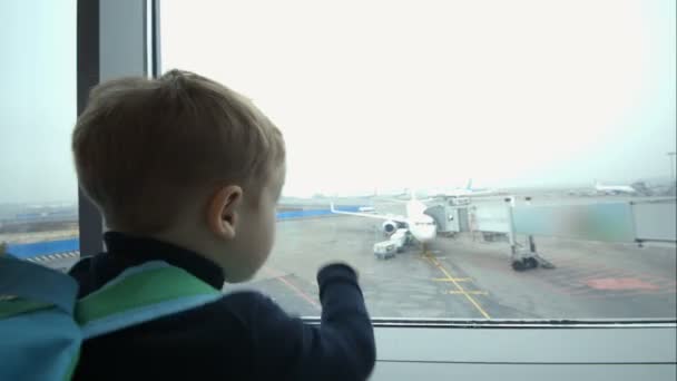 Niño mirando por la ventana y apuntando al avión — Vídeos de Stock