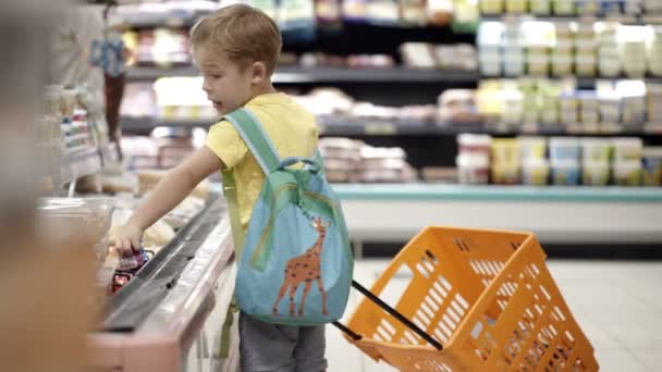 Niño poniendo productos en el carrito de la compra — Vídeo de stock