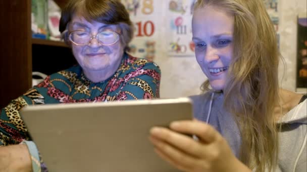 Mujer joven y mayor mirando a través de fotos en la almohadilla — Vídeo de stock