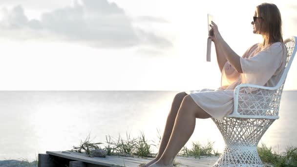 Mujer cerca del mar haciendo fotos usando almohadilla — Vídeos de Stock