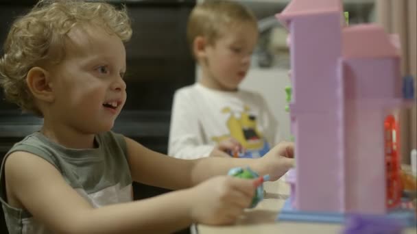 Два маленьких мальчика играют с игрушками дома — стоковое видео