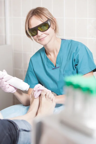 Cosmetician sorrindo que trabalha com o laser para tratar pés — Fotografia de Stock