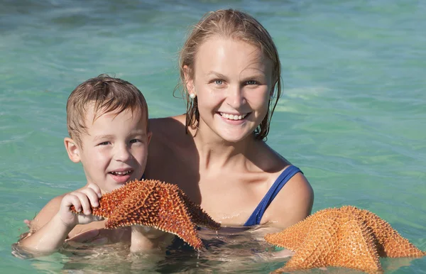 Madre e hijo en el mar sosteniendo estrellas de mar —  Fotos de Stock