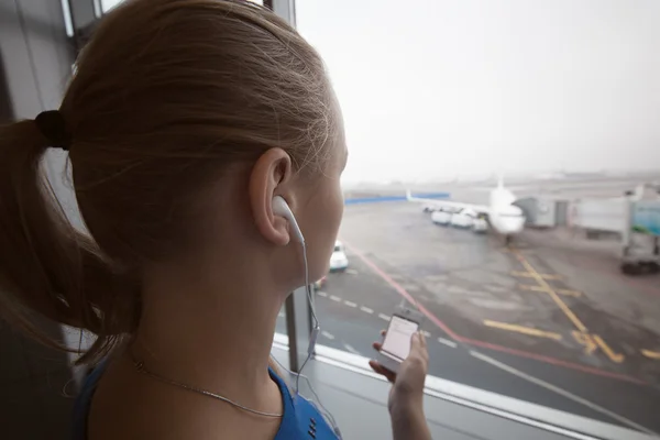 Kvinna i hörlurar tittar på flygplatsen område — Stockfoto