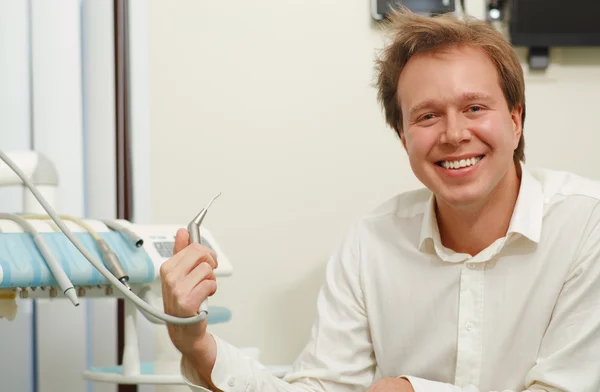 Riéndose hombre con pelo acariciado sosteniendo herramienta dental — Foto de Stock