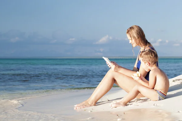 Mamma och Lille son sitter vid havet med pad — Stockfoto