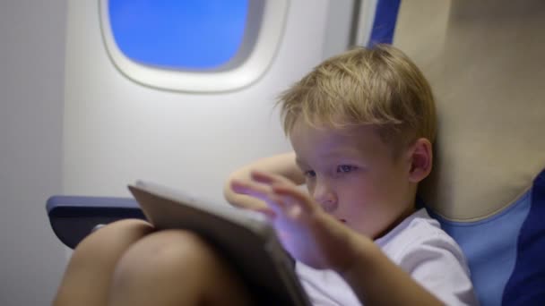 Menino entediado ou cansado em avião usando tablet — Vídeo de Stock