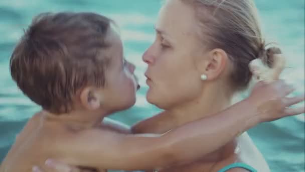 Jongen zoenen moeder tijdens het zwemmen in de zee — Stockvideo