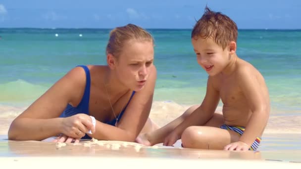 Boy watching mother drawing on sand — Stock Video