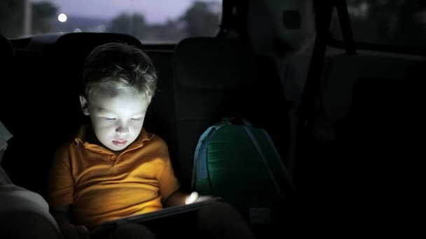 Liten pojke med hjälp av TabletPC under bilresor på natten — Stockvideo