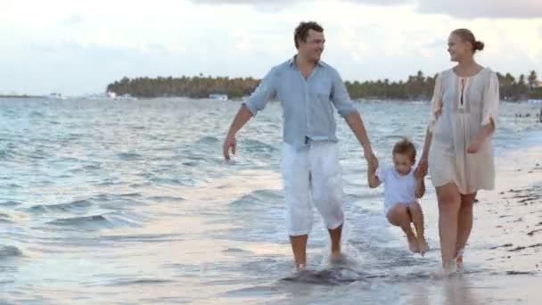 Les parents et leur enfant marchant le long de la plage — Video