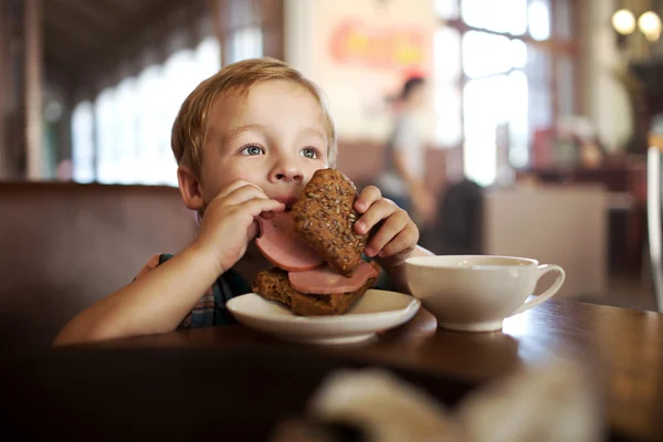 Маленька дитина обідає з бутербродом і чаєм в кафе — стокове фото