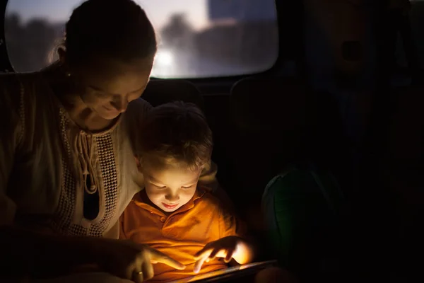 Mother and son with pad during car travel at night — Stock Photo, Image