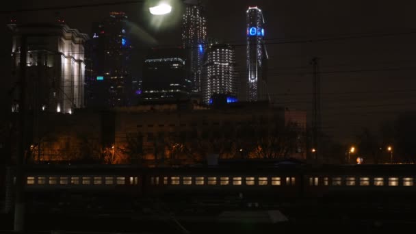 Пасажирський поїзд проходить через місто вночі — стокове відео