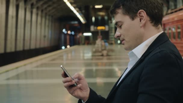 Jonge knappe zakenman texting op cel in Metro — Stockvideo