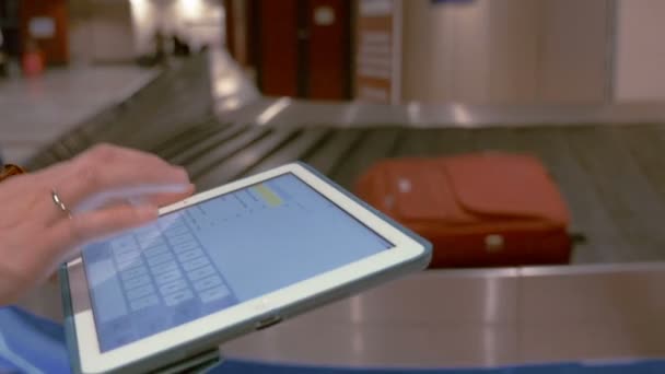 Woman using pad by the luggage conveyor belt — Stock Video